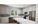 Bright kitchen featuring stainless steel appliances, white cabinetry, a breakfast bar, and a window with views of the outdoors at 338 Cottage Hill Way, Knightdale, NC 27604