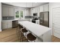 Bright kitchen featuring stainless steel appliances, white cabinetry, a breakfast bar, and a window with views of the outdoors at 338 Cottage Hill Way, Knightdale, NC 27604