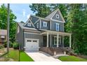 Attractive two-story home with gray siding, a front porch, white trim, and an attached garage at 415 1St St, Apex, NC 27502