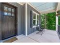 Inviting front porch with a seating area, black metal railings, and views of the surrounding greenery and home's exterior at 415 1St St, Apex, NC 27502