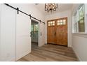 Bright foyer featuring wood-look flooring, barn door, a craftsman front door and modern light fixture at 690 Oaks Lane Rd, Timberlake, NC 27583