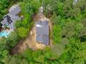 Aerial view of a home under construction, set amongst mature trees, with neighboring houses and a pool nearby at 8011 Old Trail Dr, Durham, NC 27712