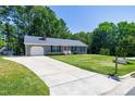 Inviting single story home with a long driveway and lush front lawn, framed by mature trees at 100 Honeysuckle Ln, Cary, NC 27513