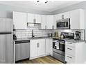 Modern kitchen featuring white cabinets, stainless steel appliances, and tiled backsplash at 1002 Willow Dr # Apt 107, Chapel Hill, NC 27514