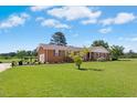 Charming brick home with a well-manicured lawn and mature trees on a sunny day at 1035 Aquilla Rd, Benson, NC 27524