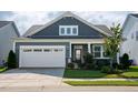 Inviting blue home featuring a two-car garage, a well-kept lawn and a cozy covered entryway at 1104 Briar Gate Dr, Holly Springs, NC 27540