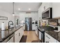 Spacious kitchen features granite countertops, stainless steel appliances, and hardwood floors at 1104 Briar Gate Dr, Holly Springs, NC 27540