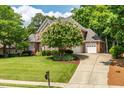 Charming brick home with a three-car garage, mature flowering tree, and well-manicured lawn at 1149 The Preserve Trl, Chapel Hill, NC 27517