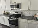 Close up of kitchen featuring stainless steel oven and microwave, granite countertops, and white cabinets at 146 Verona Villa Dr, Burlington, NC 27215
