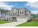 Spacious two-story home with a large yard, featuring a two-car garage and a welcoming front porch with rocking chairs at 195 Solomon Dr, Cameron, NC 28326