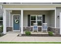 Inviting front porch with rocking chairs and a stylish front door adorned with a wreath, enhancing curb appeal at 195 Solomon Dr, Cameron, NC 28326