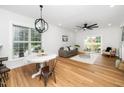 Open concept living room with hardwood floors, contemporary light fixture, gray sofa and sliding doors to backyard at 2001 Turtle Point Dr, Raleigh, NC 27604
