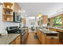 Bright kitchen featuring wood cabinets, granite countertops, stainless steel appliances, and brick flooring at 2306 Damascus Church Rd, Chapel Hill, NC 27516