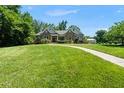 Beautiful home with a well-maintained lawn and stone facade, surrounded by lush greenery on a sunny day at 311 Rassie Crabtree Rd, Rougemont, NC 27572