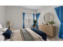 Bright bedroom with a large window, blue accents, and a stylish dresser with a round mirror at 6131 Summerpointe Pl # 101, Raleigh, NC 27606