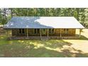 Charming stone home featuring a metal roof, expansive front yard, and inviting covered porch perfect for relaxing outdoors at 7849 Circle L Trl, Rougemont, NC 27572