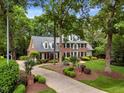 Stately brick home with manicured lawn and garden beds leads to long driveway at 116 Berry Hill Dr, Raleigh, NC 27615