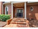 Elegant brick home featuring a charming front porch and a welcoming black front door with wreath at 1831 Middlebrook Dr, Raleigh, NC 27615