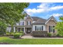 Charming two-story home with stone and siding accents, complemented by lush landscaping and a covered porch at 237 Bendemeer Ln, Rolesville, NC 27571