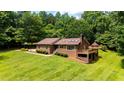 Brick home featuring a backyard deck with a gazebo, surrounded by a lush green lawn and mature trees at 2523 Lovette Ln, Graham, NC 27253