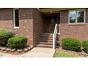 Close up view of the front door with brick steps and well-maintained landscaping with green bushes at 2523 Lovette Ln, Graham, NC 27253