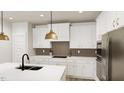 Well-lit kitchen with stainless appliances, white cabinets, backsplash, and a large island at 320 Beacon Dr, Pittsboro, NC 27312