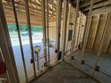 Exposed framing showing plumbing and wiring of a home under construction, with a glimpse of the garage at 4024 N Nc 581 Hwy, Kenly, NC 27542