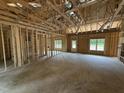 Unfinished living room featuring exposed framing, multiple windows, and a door for plenty of natural light at 4024 N Nc 581 Hwy, Kenly, NC 27542