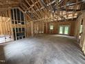 Unfinished living room showcasing exposed framing, high ceilings and natural light from exterior doors and a window at 4024 N Nc 581 Hwy, Kenly, NC 27542