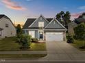 Beautiful twilight view of home with a stone and gray shake facade, complemented by a well-manicured lawn and a two-car garage at 427 Cedar Pond Ct, Knightdale, NC 27545