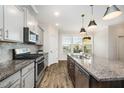 A modern kitchen featuring granite countertops, stainless steel appliances, and stylish pendant lighting at 6107 Kayton St, Raleigh, NC 27616