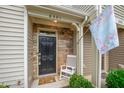 Covered porch featuring a black front door, stone accents, and a welcoming floral flag at 6301 Pesta Ct, Raleigh, NC 27612