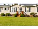 Attractive single-story home with a black door, wooden steps, landscaping, and vinyl siding at 764 Olivers Grove Rd, Four Oaks, NC 27524