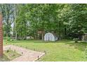 Spacious backyard featuring a storage shed, mature trees, and a treehouse at 105 Otter Dr, Cary, NC 27513