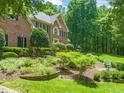 Beautifully landscaped yard with lush greenery, flowering plants, mature trees, and a charming decorative fountain at 1317 Woodgate Manor Ct, Raleigh, NC 27614