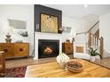 Cozy living room with a fireplace, hardwood floors, a decorative mantel, and a stylish accent wall at 137 Azalea View Way, Holly Springs, NC 27540