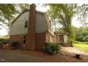 Backyard showing the rear of the house, chimney, patio, and lush trees at 1513 Western Ave, Rocky Mount, NC 27804