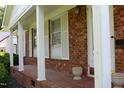 Inviting covered front porch with brick columns and a tiled floor, perfect for relaxing outdoors at 2071 Meadow Ln, Graham, NC 27253