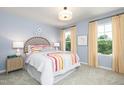 Bright bedroom with two windows, a light blue wall, and a bed with vibrant rainbow-themed bedding at 234 Macon Lake Drive # 39, Apex, NC 27523