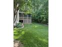 Expansive backyard with lush green grass, mature trees, and a screened porch at 4305 Heathgate Ln, Raleigh, NC 27613