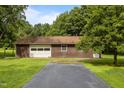 View of the detached two car garage featuring a paved driveway and surrounded by mature landscaping at 5918 Efland Cedar Grove Rd, Cedar Grove, NC 27231