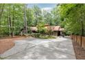 Single story home surrounded by lush greenery, a long concrete driveway, and wooded lot at 6 Womble Cir, Durham, NC 27705