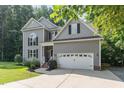 Gray two-story home with attached garage, lush front yard, and a traditional architectural design at 6717 Country Hollows Ln, Holly Springs, NC 27540