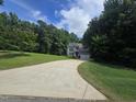 Beautiful 2-story home with gray siding and a long driveway surrounded by mature trees and landscaping at 6717 Country Hollows Ln, Holly Springs, NC 27540