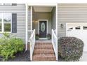 Close-up of front entrance with brick steps and black door, enhanced by potted plants at 6717 Country Hollows Ln, Holly Springs, NC 27540