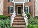 Brick home's inviting entry with stairs, white railing, and well-maintained landscaping at 7312 Sweet Bay Ln, Raleigh, NC 27615