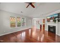 Inviting living room with hardwood floors, fireplace, large windows, ceiling fan, and an open-concept layout at 7873 Cape Charles Dr, Raleigh, NC 27617
