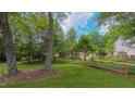 Green lawn with a split rail fence and mature trees provide a peaceful setting at 1815 Hawthorne Ln, Burlington, NC 27215