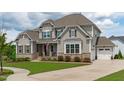 Beautiful two-story home featuring stone accents, gray siding, attached garage and a manicured lawn at 200 Baskerville Ct, Holly Springs, NC 27540