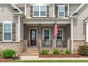Close-up of inviting front porch with stone accents, rocking chairs, and American flag at 200 Baskerville Ct, Holly Springs, NC 27540